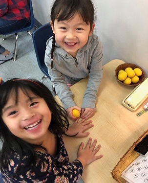 They set up their items on the back of the table. S cleans B’s nails with the egg